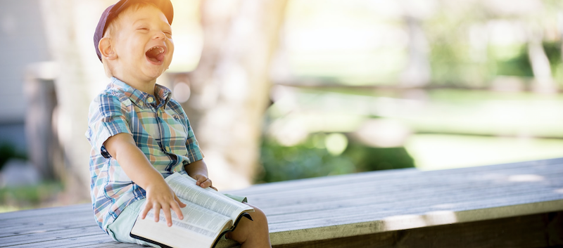 little boy on bench reading the bible, asking God