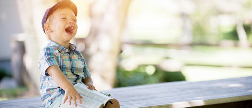 boy with Bible laughing on bench, to obey God