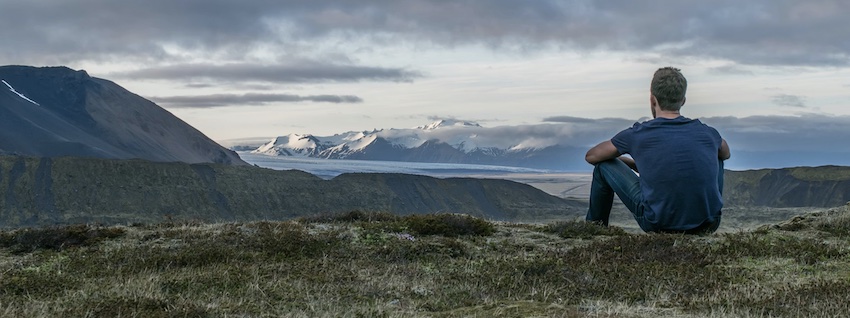 man looking at snow capped mountains, letting God